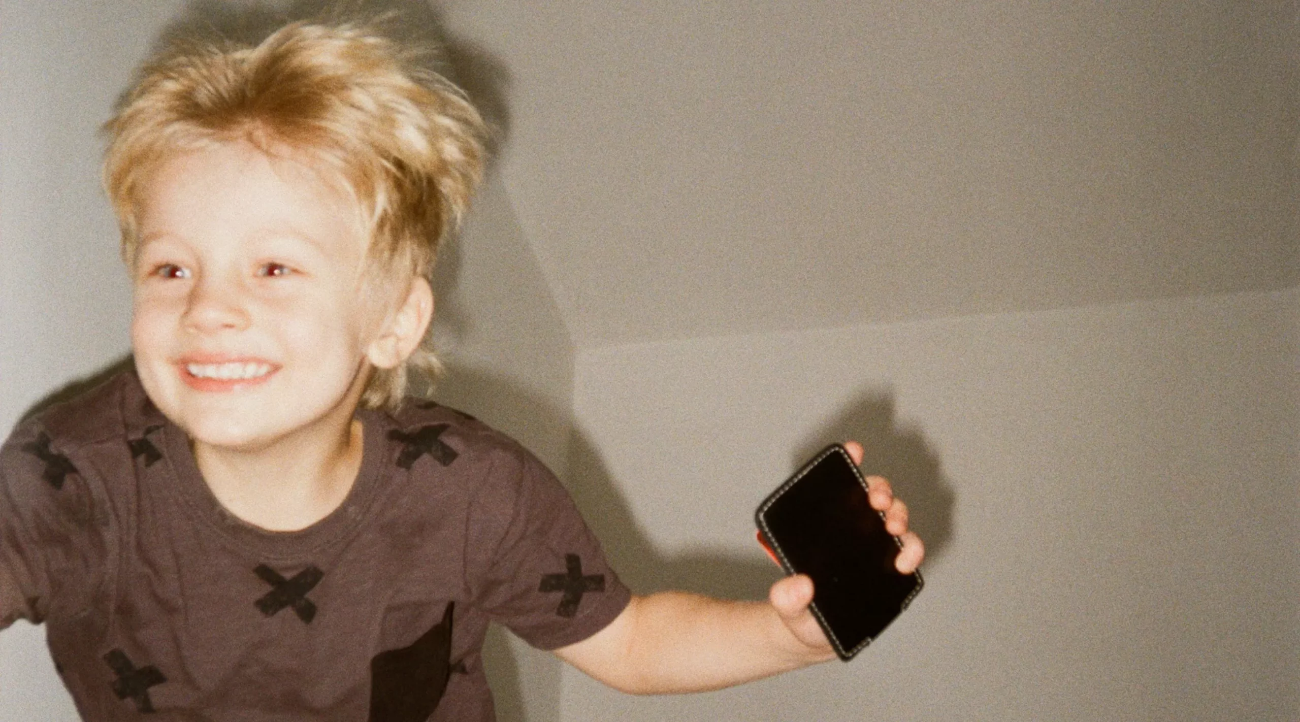 Enfant sautant sur un lit un téléphone à la main