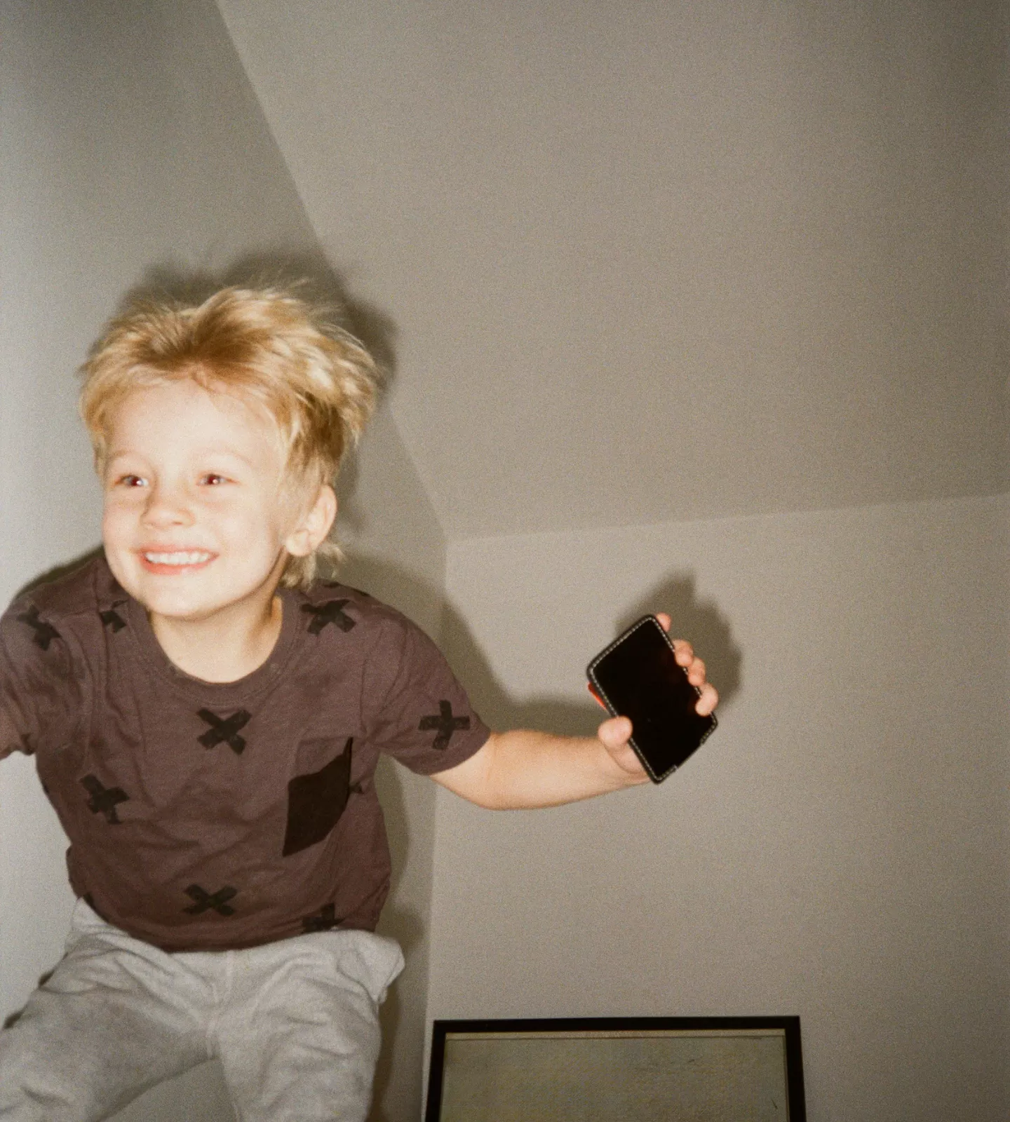 Enfant sautant sur un lit un téléphone à la main